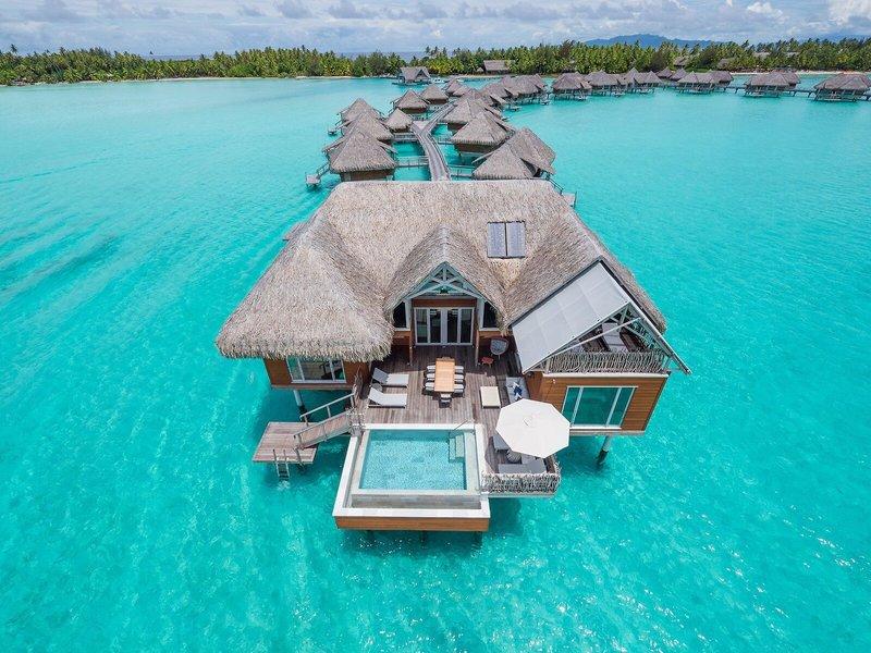 Ein InterContinental Bora Bora Wasserbungalow mit Pool und Sonnenschirm.
