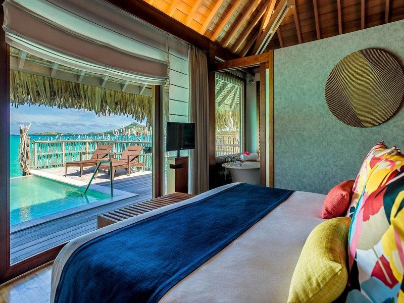Ein komfortables Bett mit farbenfrohen Kissen und Blick auf das Meer im InterContinental Bora Bora.