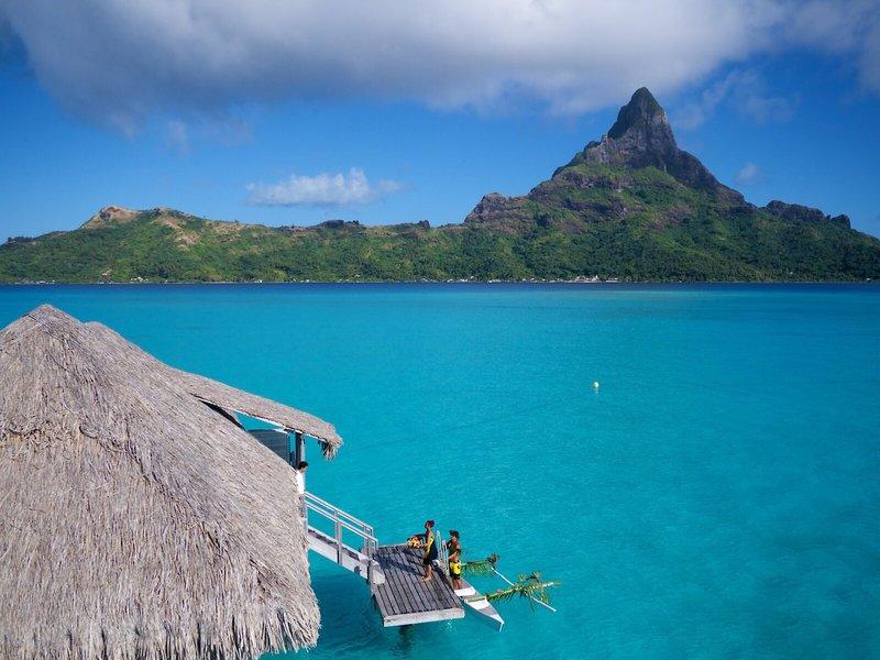 Aussicht auf das InterContinental Bora Bora Resort und Thalasso Spa mit kristallklarem Wasser und Bergen im Hintergrund.