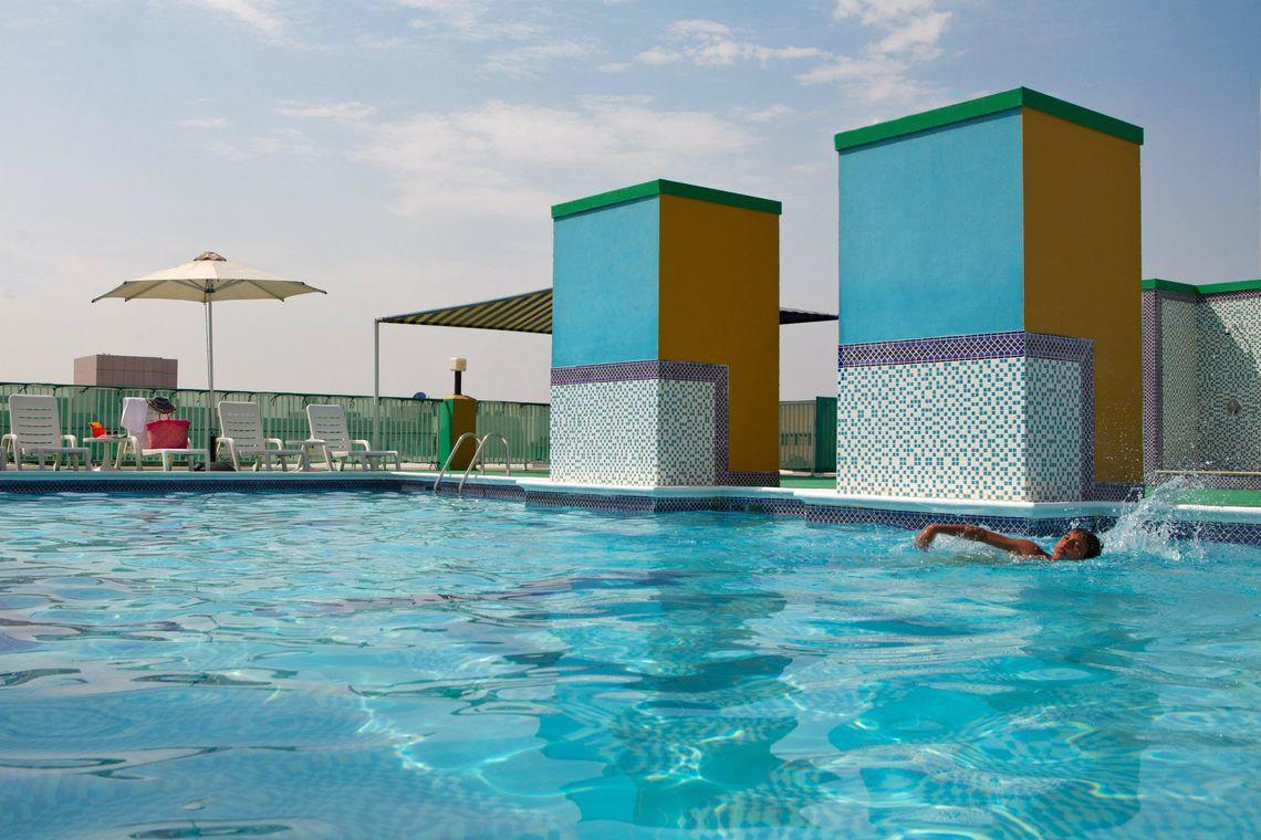 Schwimmbad auf dem Dach des Golden Sands Hotel Apartments mit einer Person, die schwimmt.
