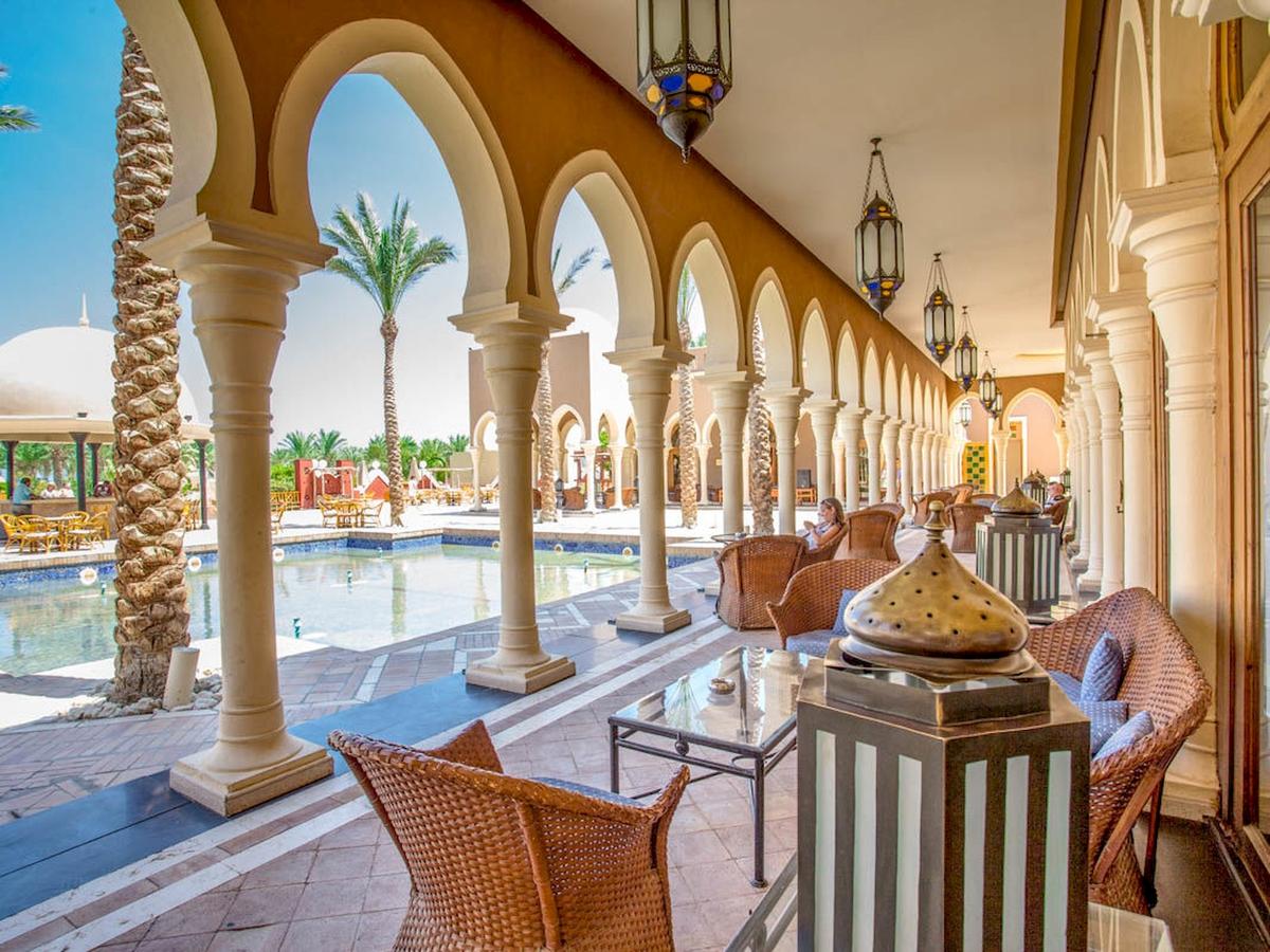 Loungebereich des Grand Makadi Hotels mit bogenförmigen Säulen und einem Pool im Hintergrund.