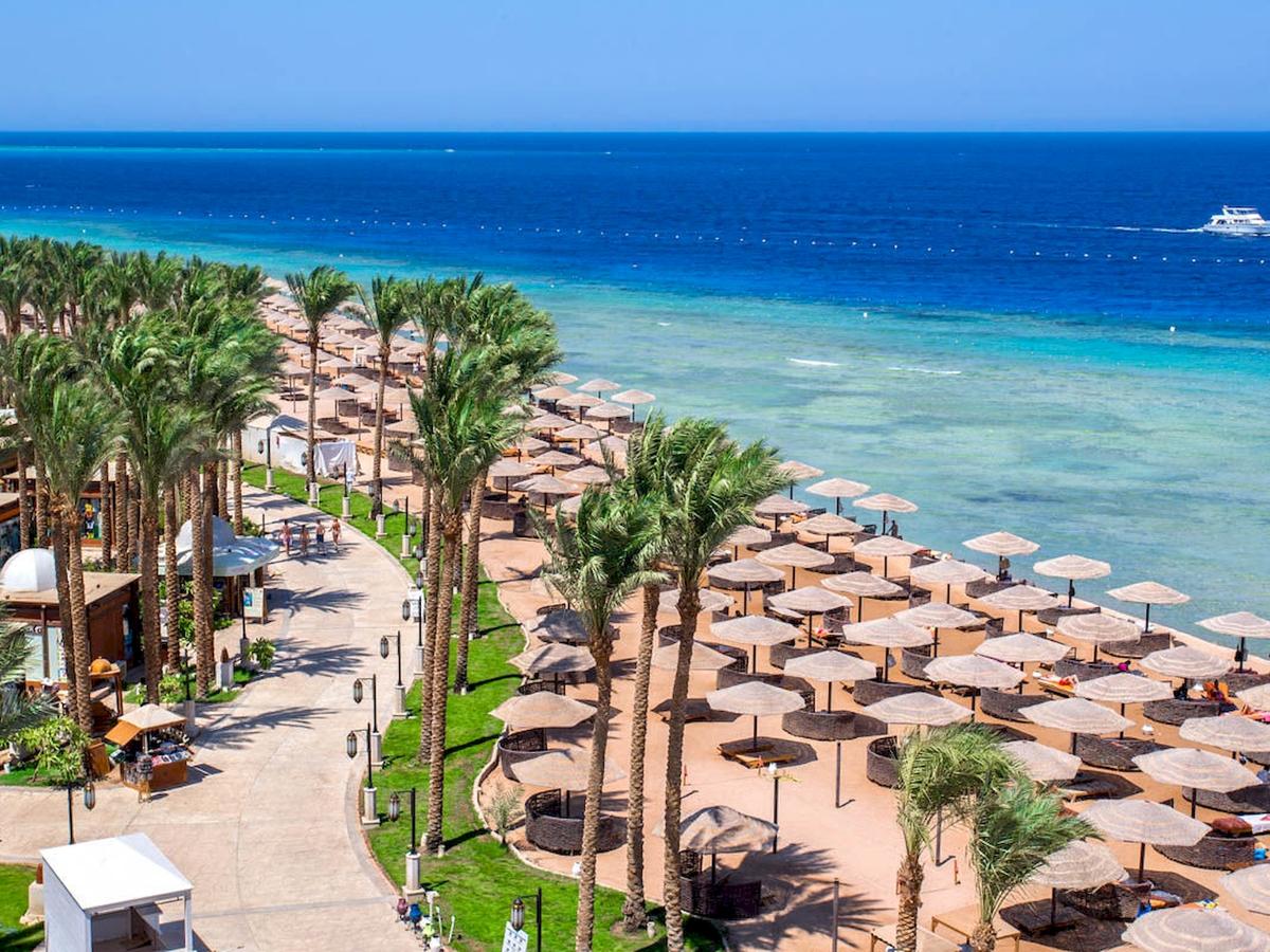 Luftaufnahme des Grand Makadi Hotels mit breitem Strand und vielen Sonnenschirmen.