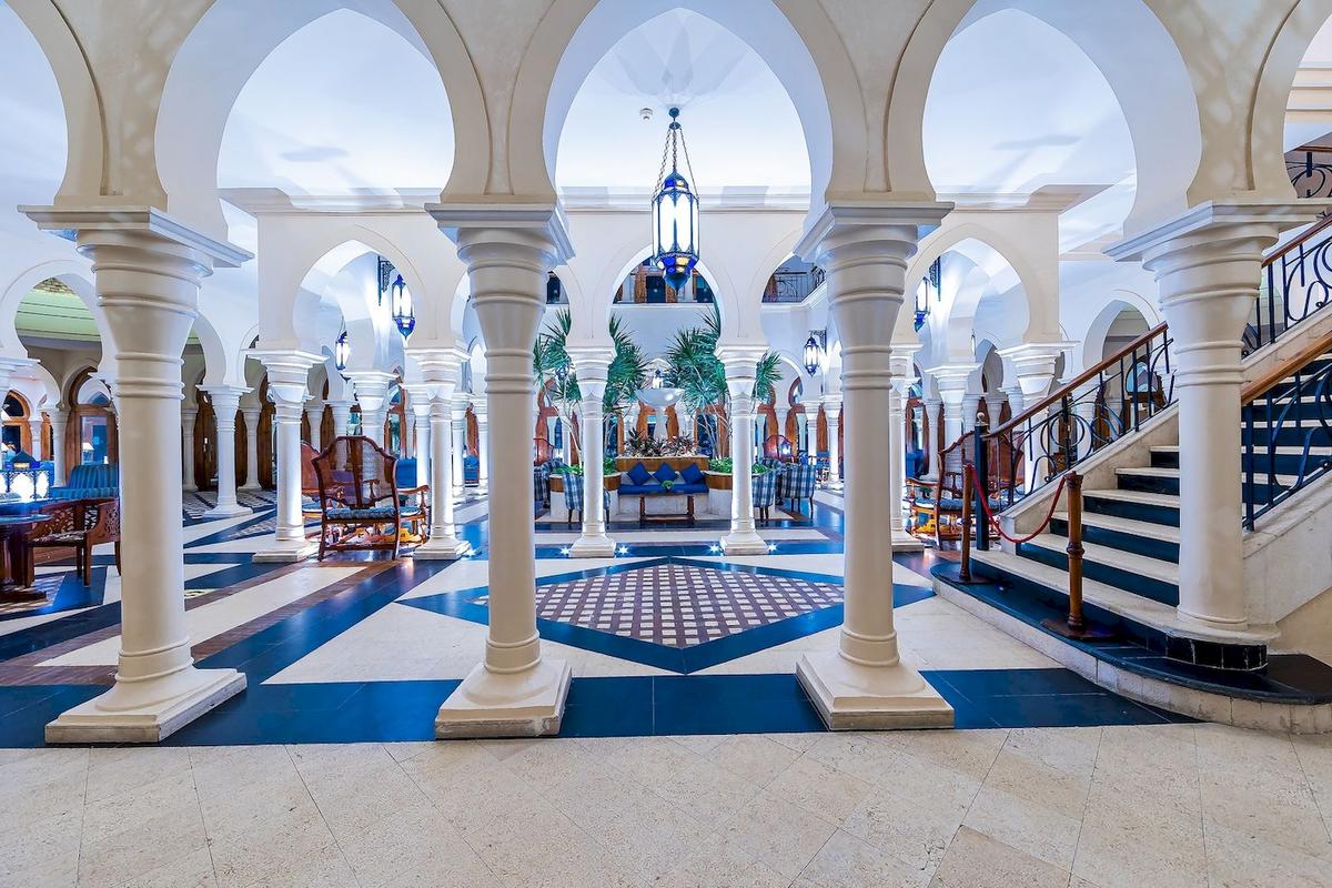 Empfangsbereich des Grand Makadi Hotels mit weißen Säulen und blauen Bodenfliesen.