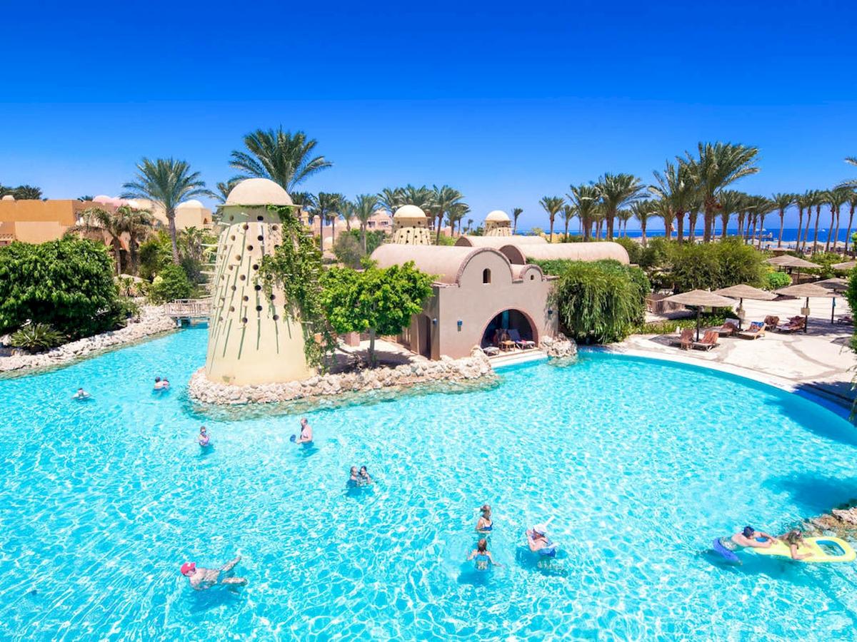 Außenansicht des Swimmingpools im Grand Makadi Hotel mit Gästen und Palmen
