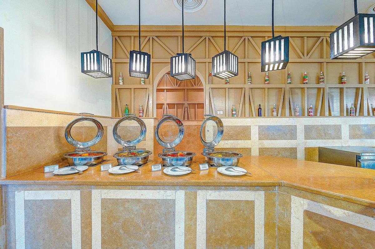 Buffet-Tisch im Grand Makadi Hotel mit Speisen in Metallschüsseln und hängenden Laternen.