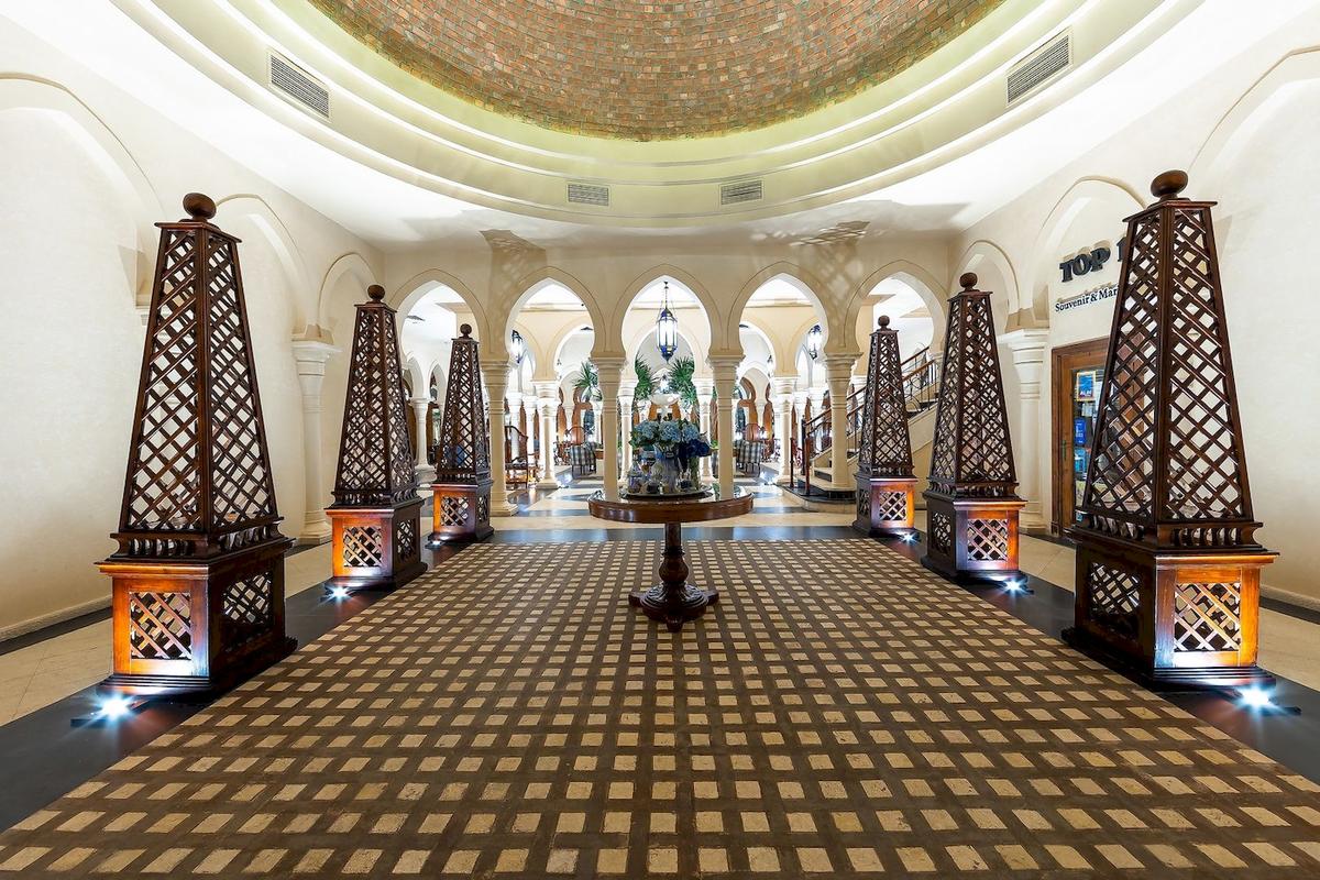 Der Eingangsbereich des Grand Makadi Hotels mit geometrischem Musterboden und dekorativen Holzsäulen.