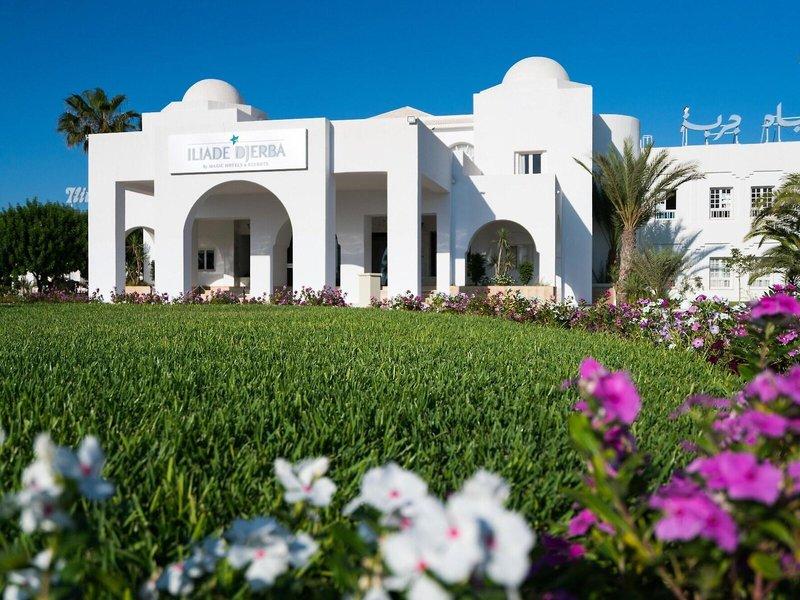 Frontansicht des Iliade Djerba Hotels mit weißem Gebäude und grünem Rasen