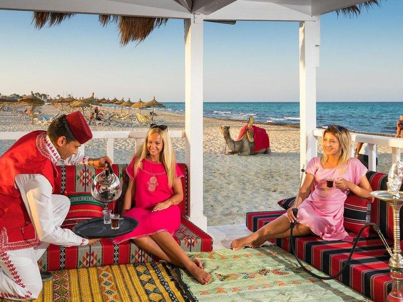 Bediensteter serviert Cocktails auf der Terrasse des Iliade Djerba by Magic Hotels.