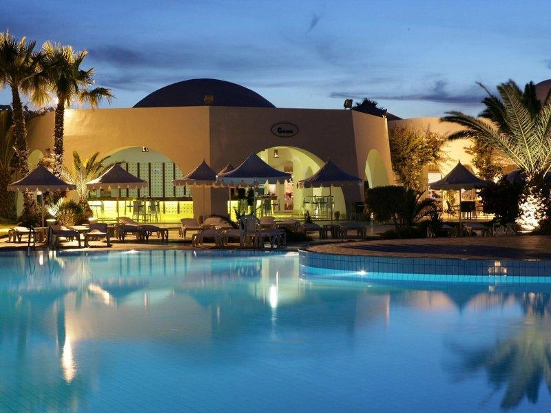 Außenbereich des Iliade Djerba by Magic Hotels mit Pool und Loungemöbeln bei Nacht