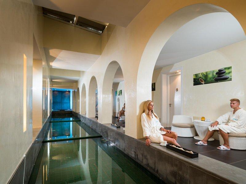 Das Relax-Bereich des Iliade Djerba by Magic Hotels mit einem Schwimmbad und zwei Personen in Bademänteln.