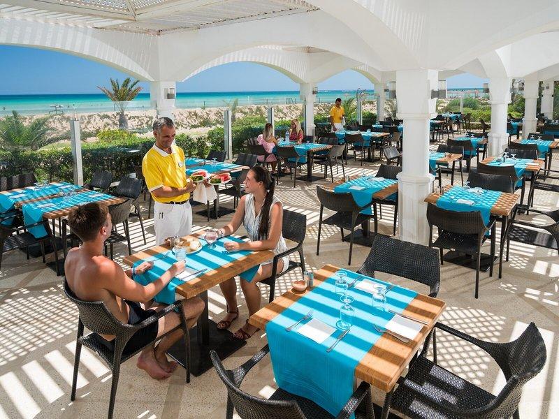 Bedienung serviert Gäste im Freien Restaurant des Iliade Djerba by Magic Hotels