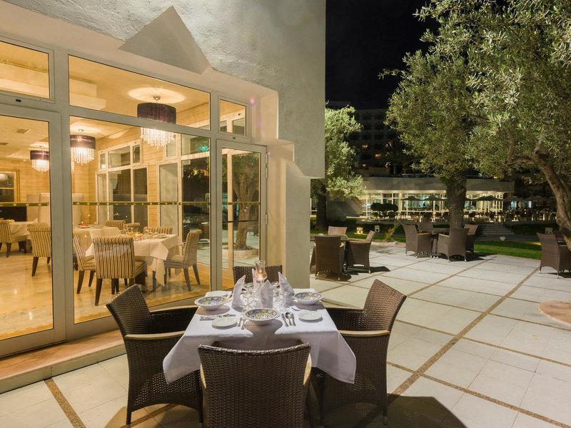 Außenbereich des JAZ Tour Khalef Hotels mit Tisch und Stühlen, bei Nacht.