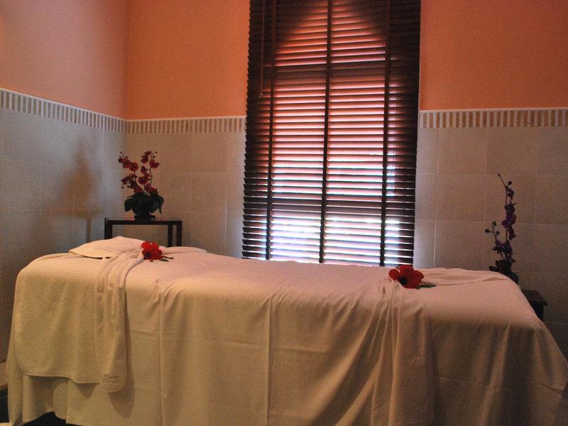 Massage-Behandlungsraum im JAZ Tour Khalef mit einem Massagetisch, weißen Laken, roten Rosen und geschlossenen Jalousien.