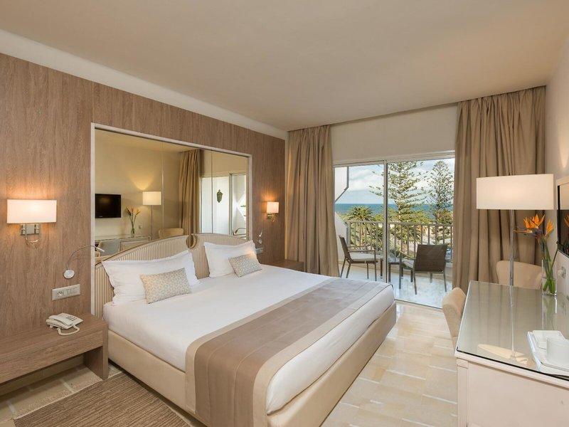 Ein modernes Hotelzimmer mit einem großen Bett, einem Balkon und Meerblick im JAZ Tour Khalef Hotel.
