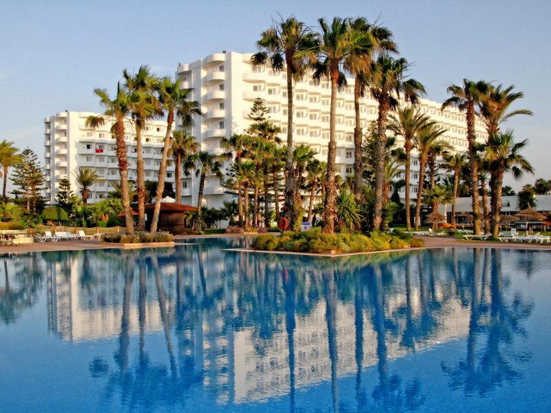 Außenpool des Sahara Beach AquaPark Resorts mit weißen Gebäuden im Hintergrund und Palmen