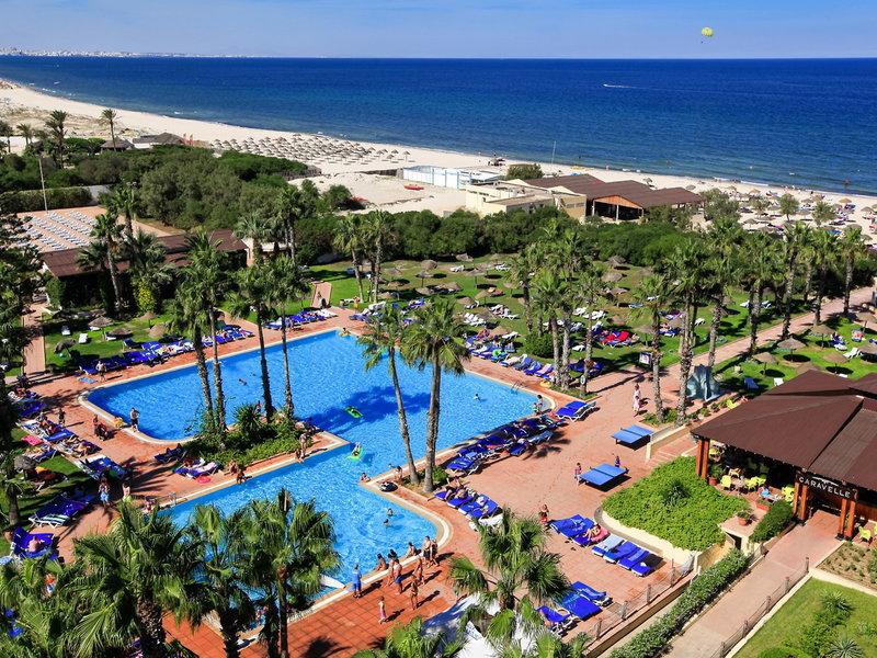 Luftaufnahme des Sahara Beach AquaPark Resorts mit zwei Swimmingpools, Liegestühlen und Palmen