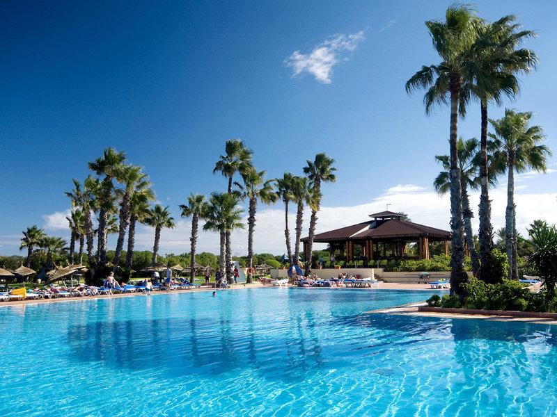 Außenpool des Sahara Beach AquaPark Resorts mit Lounge-Sesseln und Palmen
