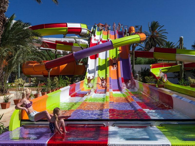 Farbige Wasserrutsche im Sahara Beach AquaPark Resort mit mehreren Personen, die darauf fahren.