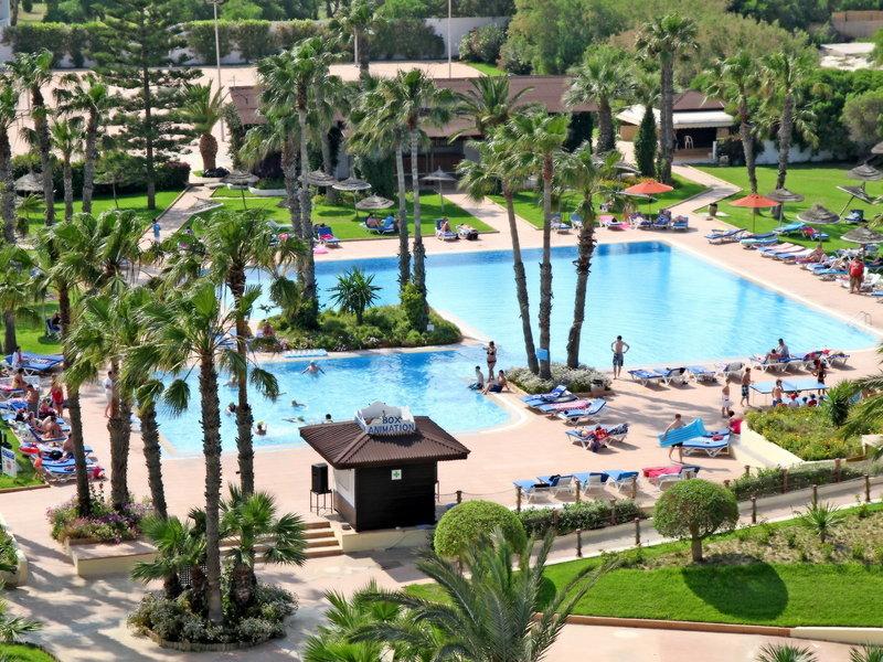 Außenansicht des Sahara Beach AquaPark Resorts mit zwei großen Swimmingpools, Sonnenschirmen und Liegestühlen.