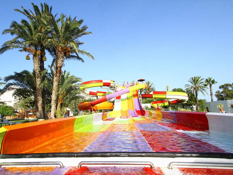 Farbige Wasserrutsche im Sahara Beach AquaPark Resort mit Palmen im Hintergrund.