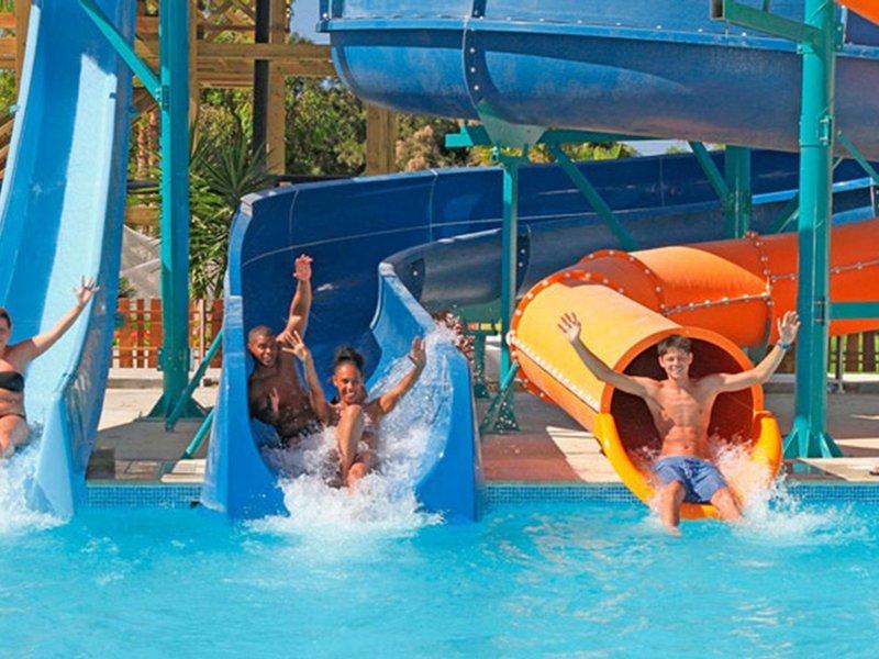 Gruppe von Menschen rutscht auf blauen und orangefarbenen Wasserrutschen im Sahara Beach AquaPark Resort.