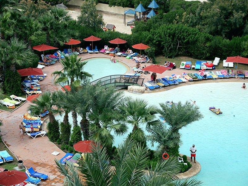 Einen Überblick über das Sahara Beach AquaPark Resort mit Swimmingpool, Liegestühlen und Sonnenschirmen.