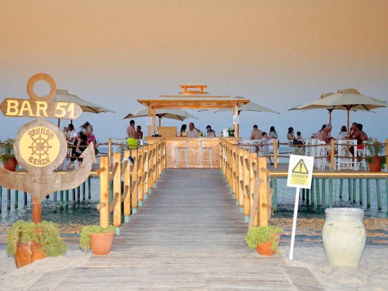Sahara Beach AquaPark Resort Bar 51 am Wasser mit Gästen, Sonnenschirmen und Tischen.