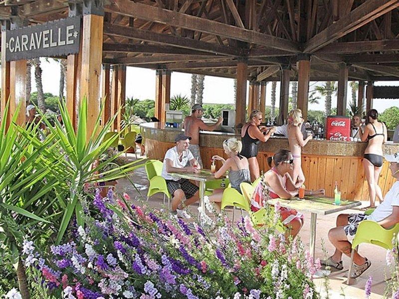 Gäste sitzen an Tischen auf der Terrasse des Caravelle im Sahara Beach AquaPark Resort.