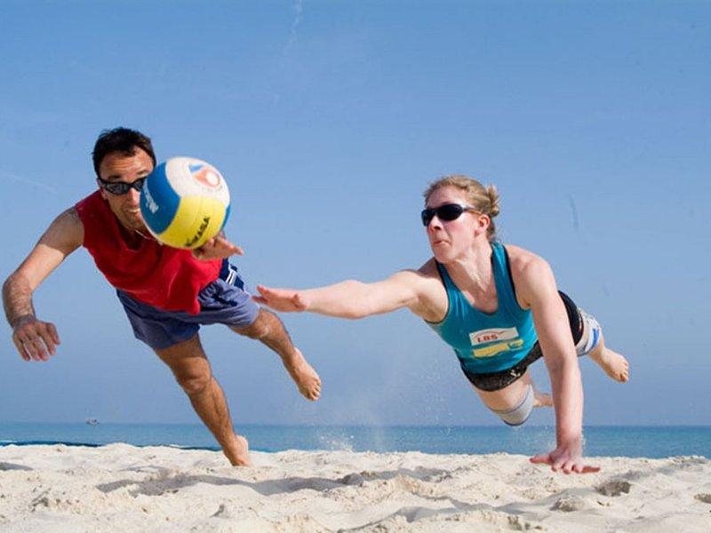 Ein Mann und eine Frau spielen Volleyball am Strand.
