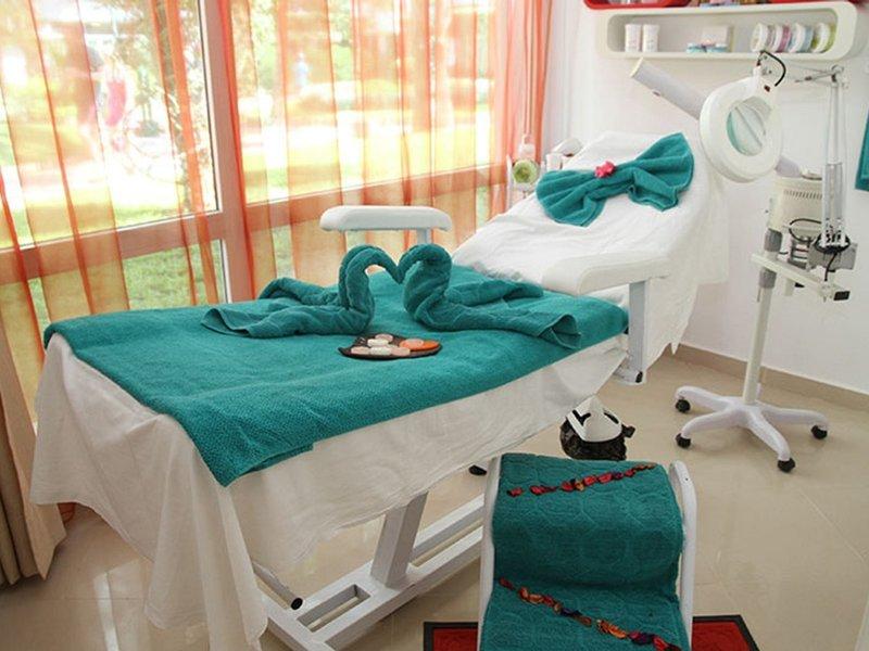 Behandlungszimmer im Sahara Beach AquaPark Resort mit grünen Handtüchern und Blick auf den Garten.