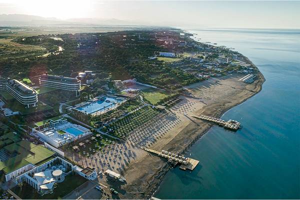 Luftaufnahme des Voyage Belek Golf & Spa Resorts mit mehreren Pools und einer langen Strandlinie.