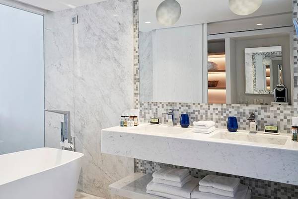 Luxuriöses Badezimmer im Myconian Ambassador Relais & Chateaux mit Badewanne, Doppelwaschbecken und Marmorfliesen.
