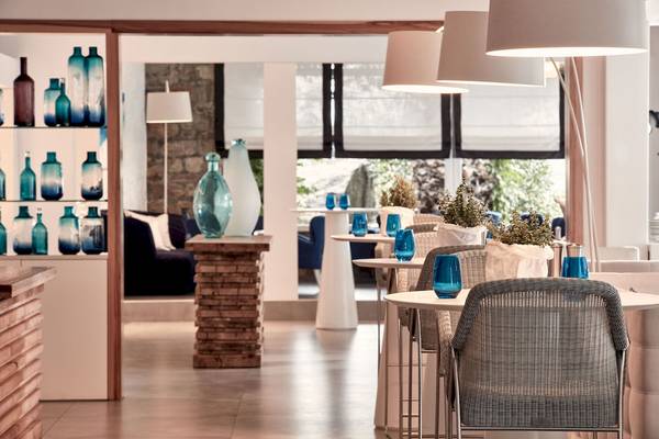 Innenbereich des Myconian Ambassador Hotels mit modernen Möbeln, blauen Gläsern und Pflanzen.