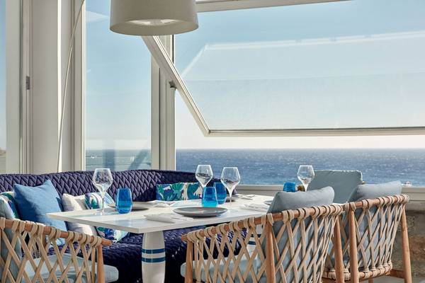 Tisch im Myconian Ambassador Hotel mit Meerblick, blaue Kissen und Gläser.