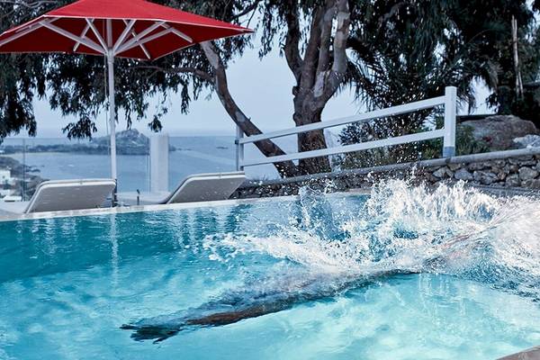 Schwimmer im Pool des Myconian Ambassador Hotels mit rotem Sonnenschirm