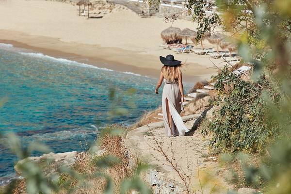 Gast des Myconian Ambassador Relais & Chateaux auf einer Felskante am Strand