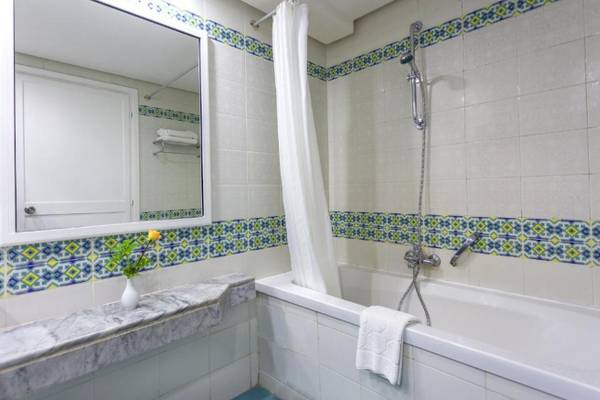 Badezimmer im Djerba Holiday Beach Hotel mit Badewanne, Spiegel und Waschbecken.