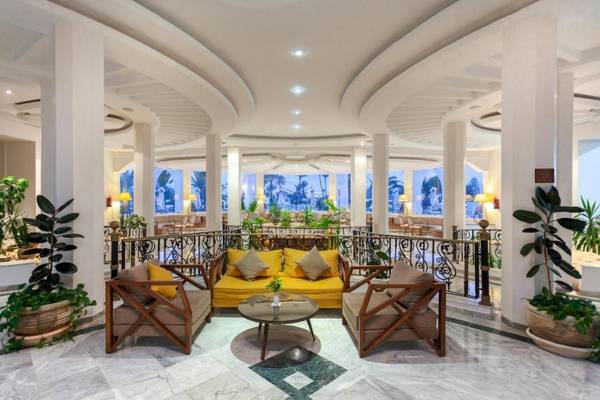 Lobby des Djerba Holiday Beach Hotels mit gelber Couch, Tischen und Pflanzen.