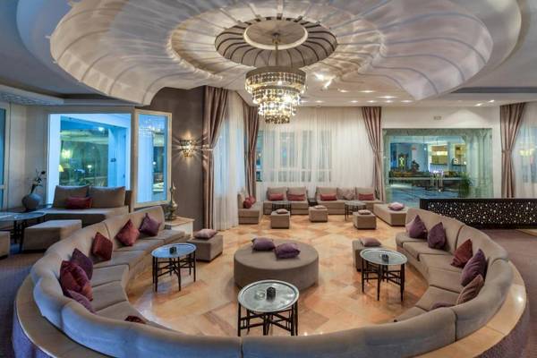 Lobby des Djerba Holiday Beach Hotels mit großen Sofas, Tischen und einer beeindruckenden Deckenleuchte.