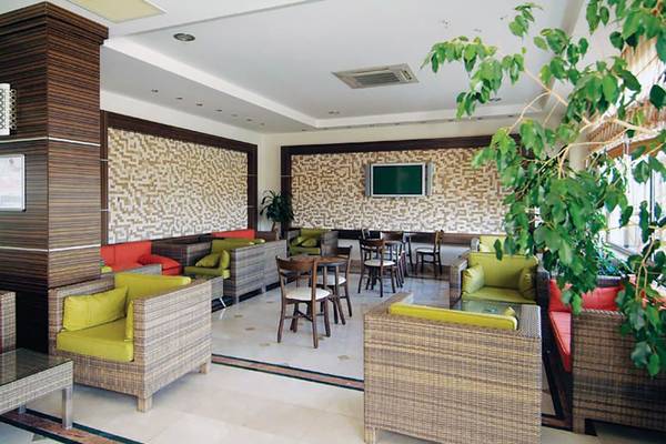 Der geräumige Loungebereich des Fun&Sun Smart Hane sun Hotels mit gepolsterten Sofas, Tischen und einer gemusterten Wand.