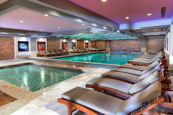 Innenpool im Crystal Deluxe Resort & Spa mit Lounge-Liegestühlen und farbiger Beleuchtung.