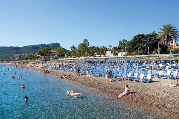 Strand des Crystal Deluxe Resort & Spa mit vielen Liegestühlen und Gästen