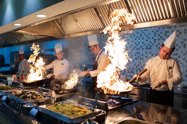 Küchenchefs im Crystal Deluxe Resort & Spa bereiten Gerichte zu und entzünden Flammen in der Küche.