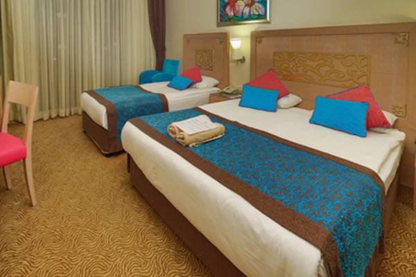 Zwei Betten im Hotelzimmer des Crystal Deluxe Resort & Spa mit blauen und roten Kissen.