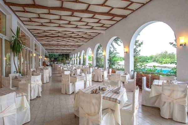 Innenbereich des Restaurants im Irene Palace Beach Resort mit gedeckten Tischen und Säulen.