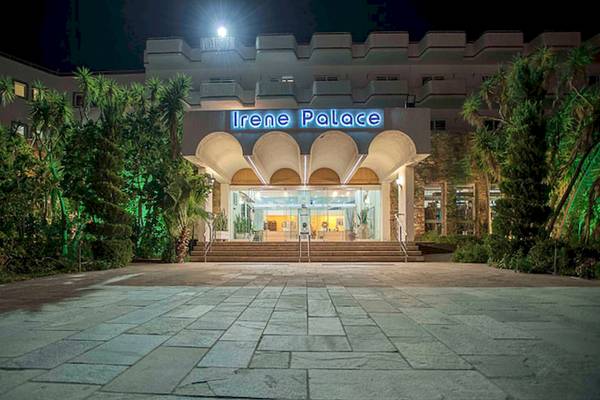 Außenansicht des Irene Palace Beach Resorts bei Nacht mit Beleuchtung und Pflanzen davor.