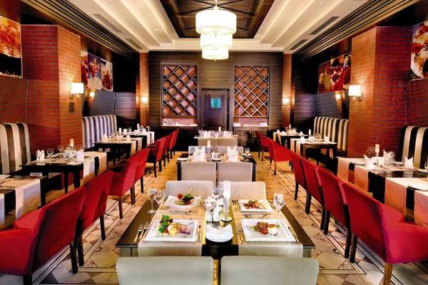 Innenansicht des Restaurants im Crystal Deluxe Resort & Spa mit roten Stühlen und geometrischem Bodenmuster.