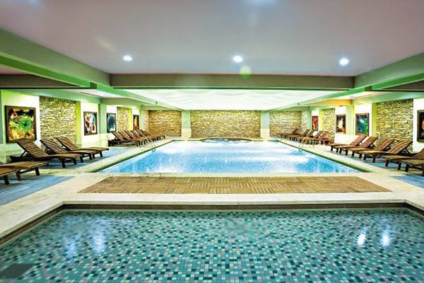 Innenpool des Crystal Deluxe Resort & Spa mit blauen Kacheln und Loungeliegen.
