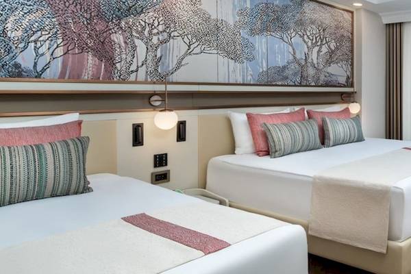 Doppelzimmer im Delphin Palace Hotel mit zwei Betten, Sofa, Schreibtisch und Terrassentür.
