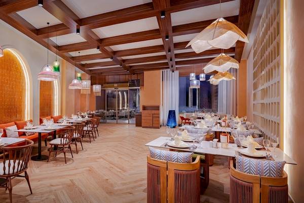 Innenbereich des Delphin Palace Restaurants mit orangefarbenen Wänden, Holztischen und Stühlen.